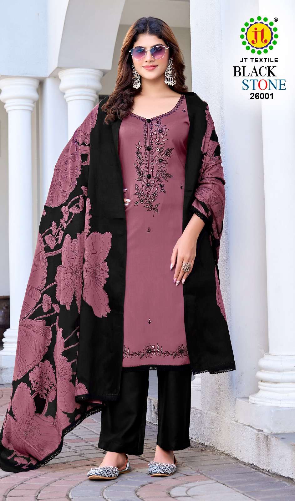 Woman wearing a black and pink traditional outfit with a floral dupatta, standing in front of white columns. | JT TEXTILE BLACK STONE VOL-26 26001 TO 26005 SERIES PURE RAYON EMBROIDERY PAKISTANI DRESSES