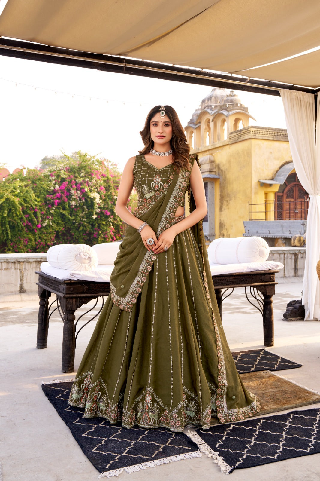 Woman in a green traditional outfit standing outdoors with a building and garden in the background | Taraa L 1457 Chocolate Crush Embroidery Worked Beautiful Lehenga Choli Collection