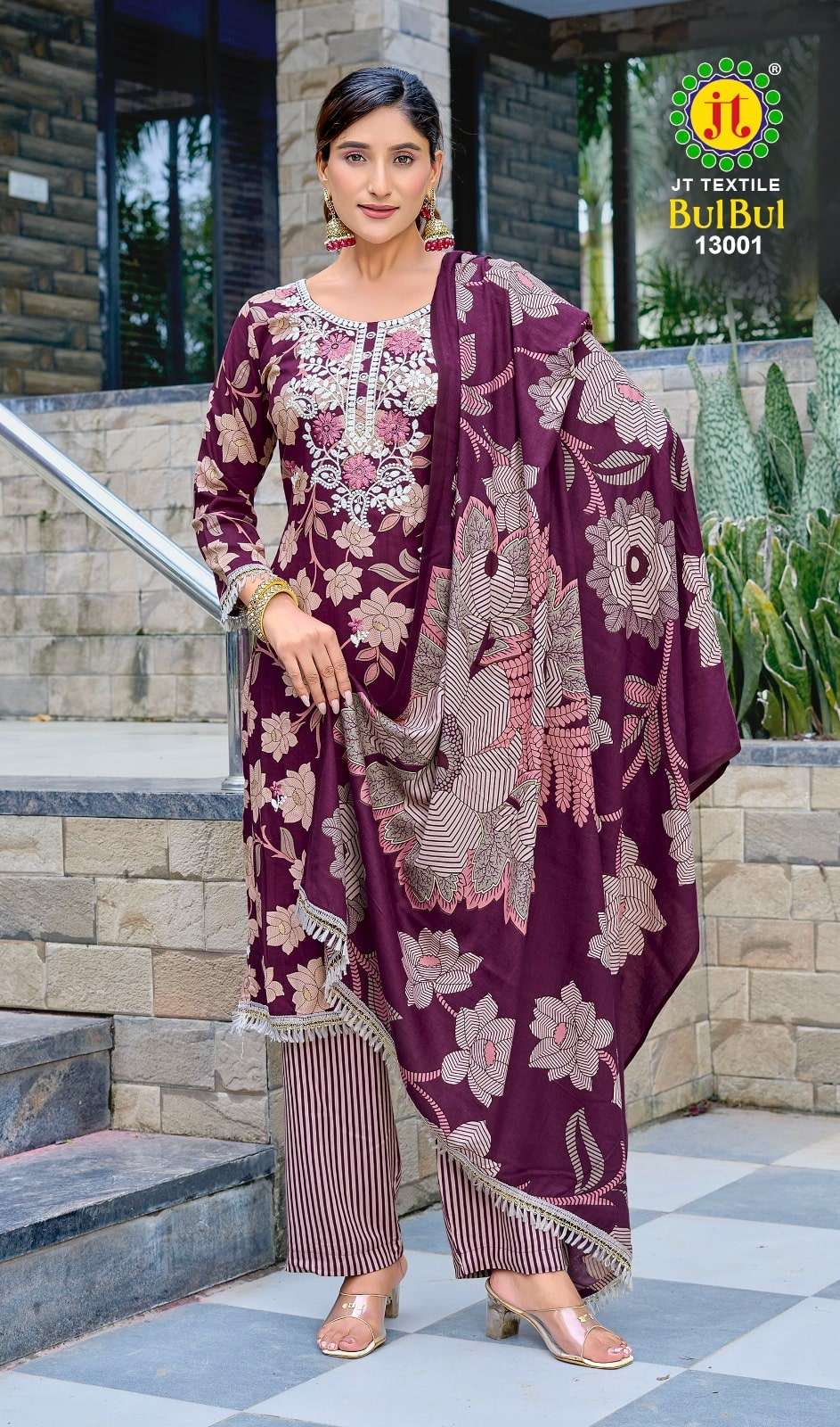 Woman wearing a purple floral outfit with a matching dupatta, standing outdoors.