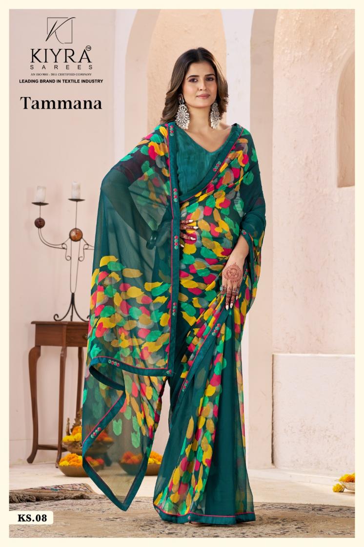 Woman wearing a teal saree with colorful patterns in an elegant indoor setting. | Kiyra Presents Tammana Georgette Fancy Sarees