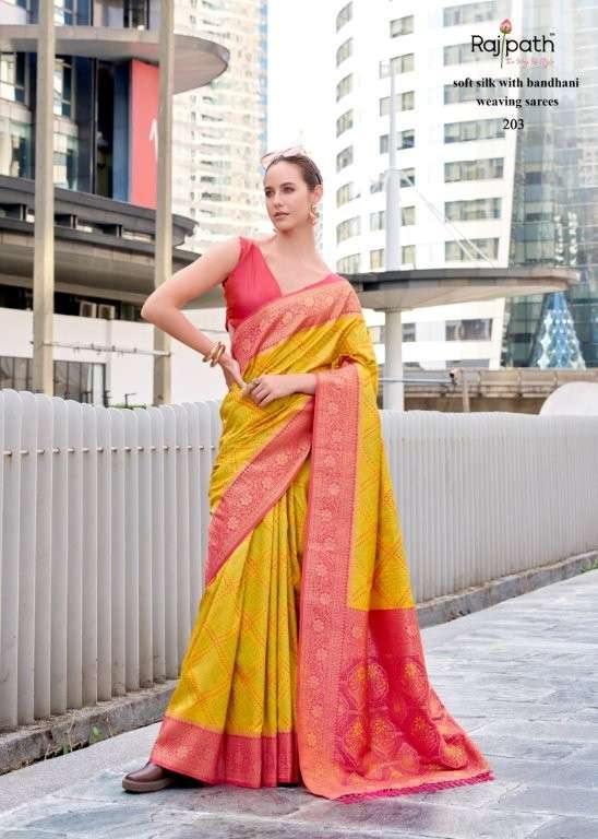 Woman wearing a yellow and pink saree with a cityscape background | RAJPATH Sugandh Silk Pure Silk Bandhani Sarees Catalogue