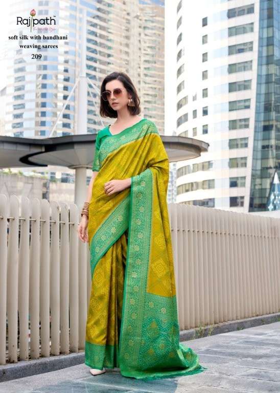Woman wearing a green and yellow saree with a cityscape background | RAJPATH Sugandh Silk Pure Silk Bandhani Sarees Catalogue