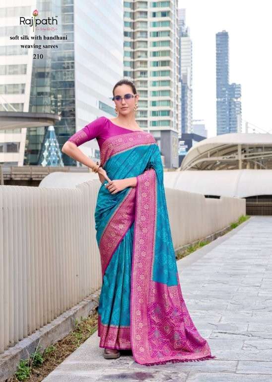 Woman wearing a blue and pink saree with a cityscape background | RAJPATH Sugandh Silk Pure Silk Bandhani Sarees Catalogue