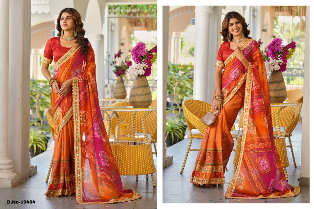 Woman in a vibrant orange and pink saree standing in an outdoor setting with tables and chairs. | SWARNA 19401 TO 19405 SERIES PURE CHIFFON EMBROIDERY SAREES