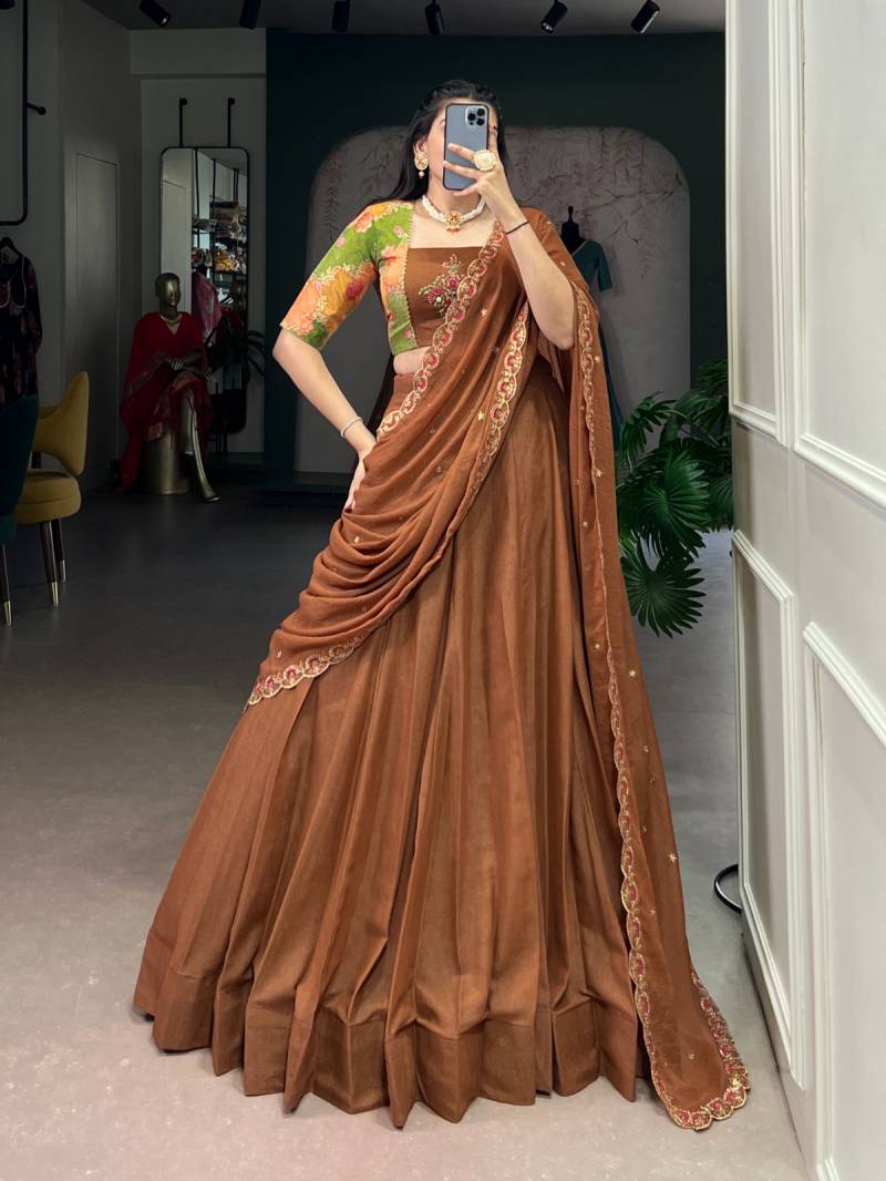 Person wearing a brown saree with gold embroidery in a room setting. | Taraa L 1068 Chocolate Crush Plain Lehenga Choli Collection
