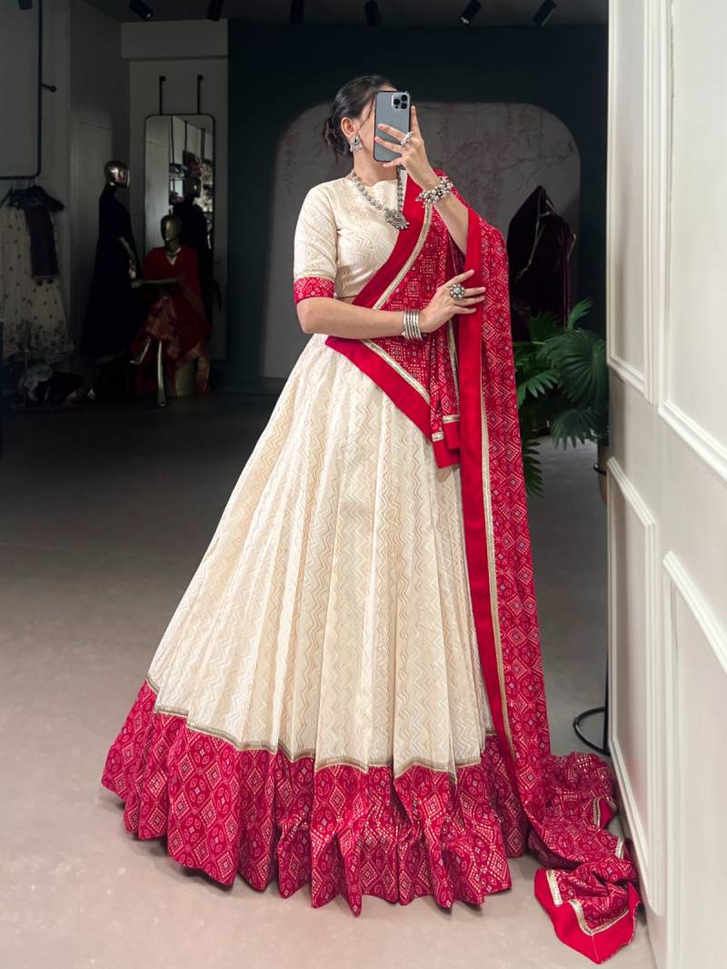 Woman in a white and red saree taking a mirror selfie. | Taraa L 1669 Cotton Bandhani Printed Fancy Lehenga Choli Collection