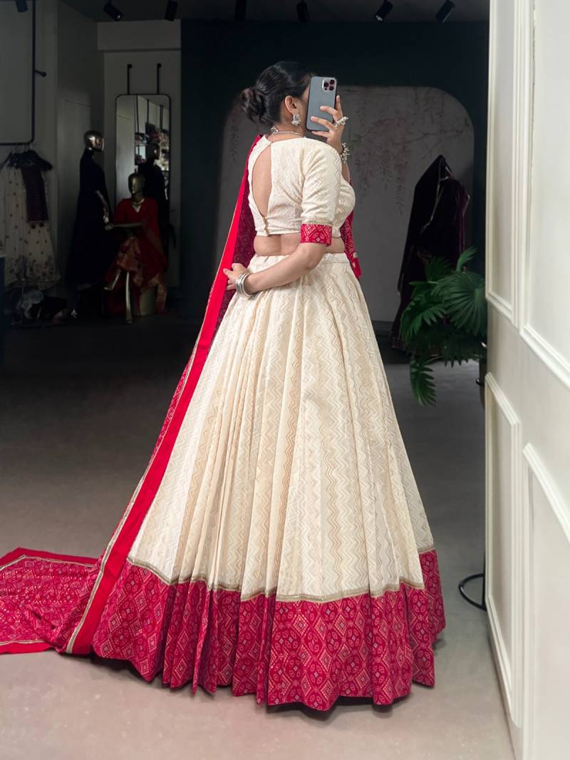 Woman in a cream and red traditional outfit taking a mirror selfie. | Taraa L 1669 Cotton Bandhani Printed Fancy Lehenga Choli Collection