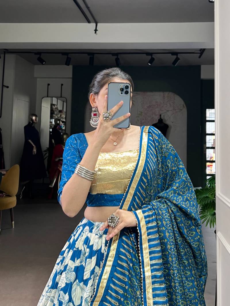 Person wearing a blue and gold traditional outfit taking a mirror selfie. | Taraa L 1725 Tussar Silk Printed With Foil Worked Lehenga Choli Collection Full Catalog Available at Wholesale Rate