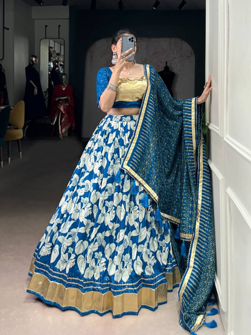 Woman in a blue and white floral lehenga with a matching dupatta, standing indoors. | Taraa L 1725 Tussar Silk Printed With Foil Worked Lehenga Choli Collection Full Catalog Available at Wholesale Rate