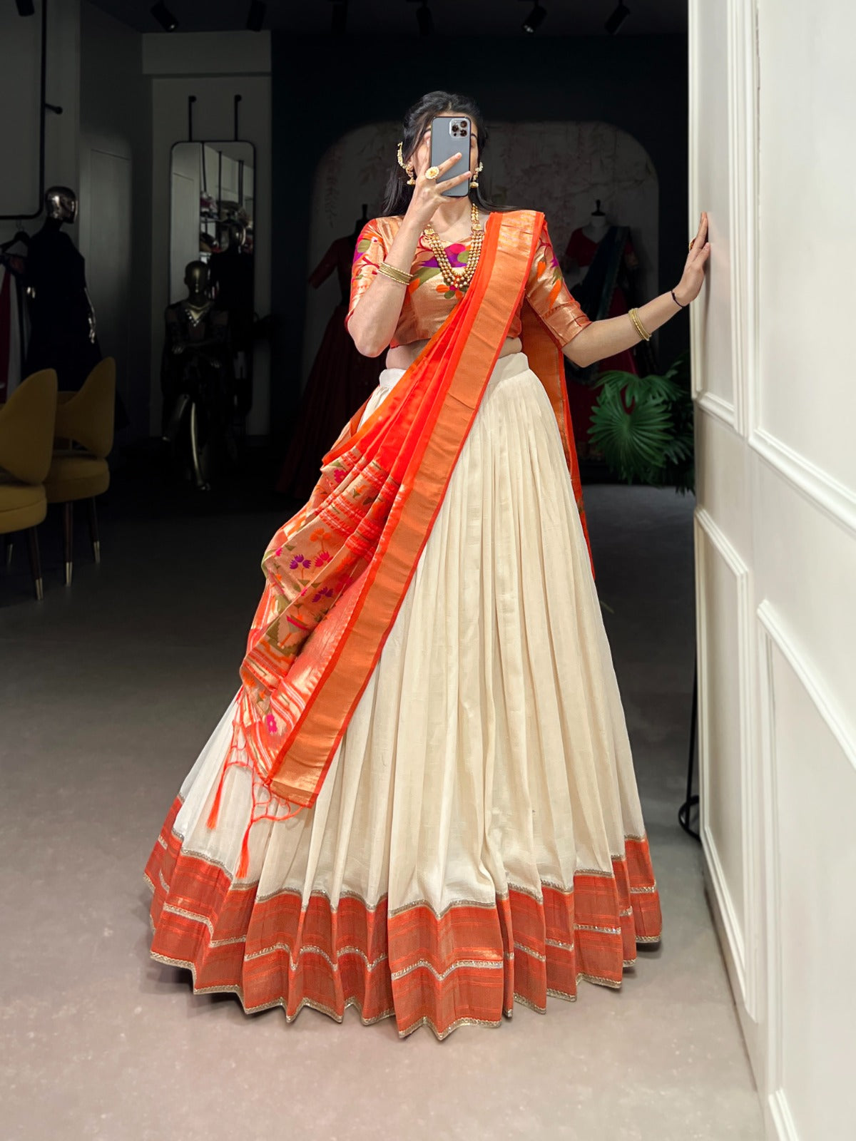 Woman wearing a traditional outfit with an orange and white saree in a room. | Taraa L 2007 Vichitra Silk Zari Weaving Plain Lehenga Choli Collection