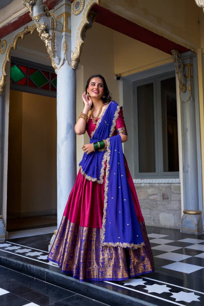 Woman in a traditional blue and pink saree standing in an ornate doorway. | Taraa L 2023 Narayan Pattu Zari Worked Designer Lehenga Choli Collection