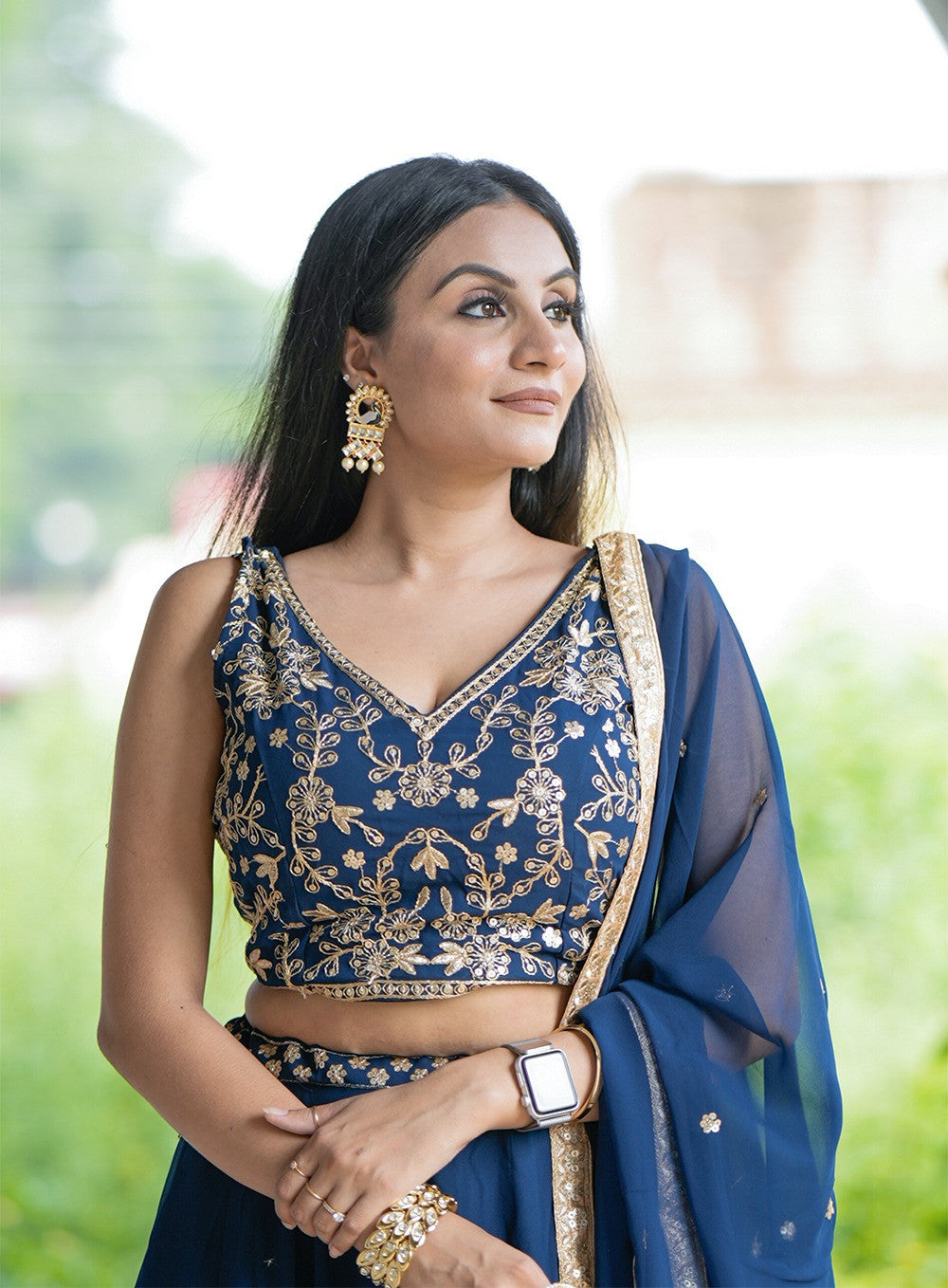 Woman in a blue embroidered saree with gold details outdoors | V3 366 Faux Georgette Embroidered Designer Lehenga Choli Wholesale Price